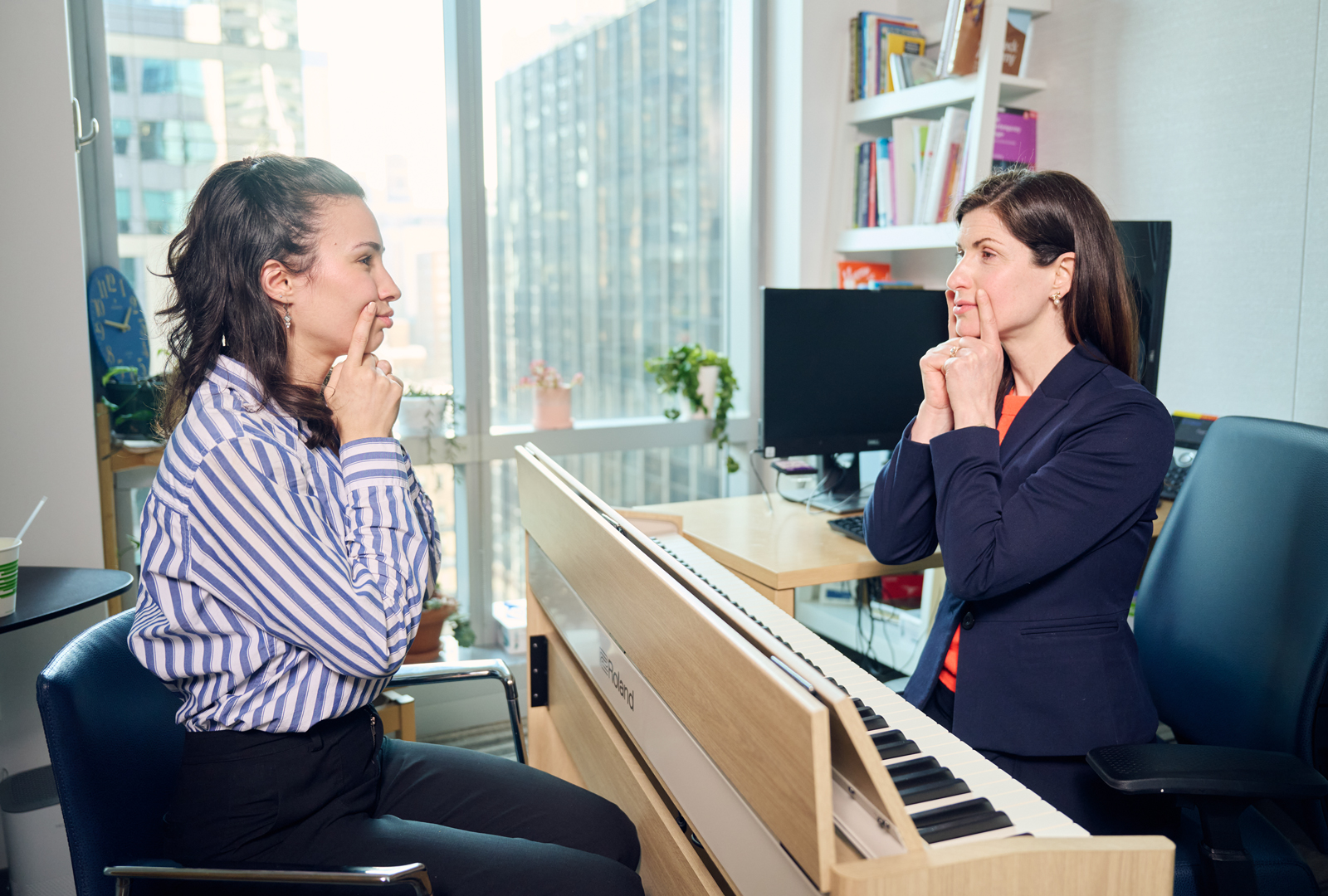 Provider seated at piano across from patient leads facial exercises involving placing index fingers on each side of the mouth