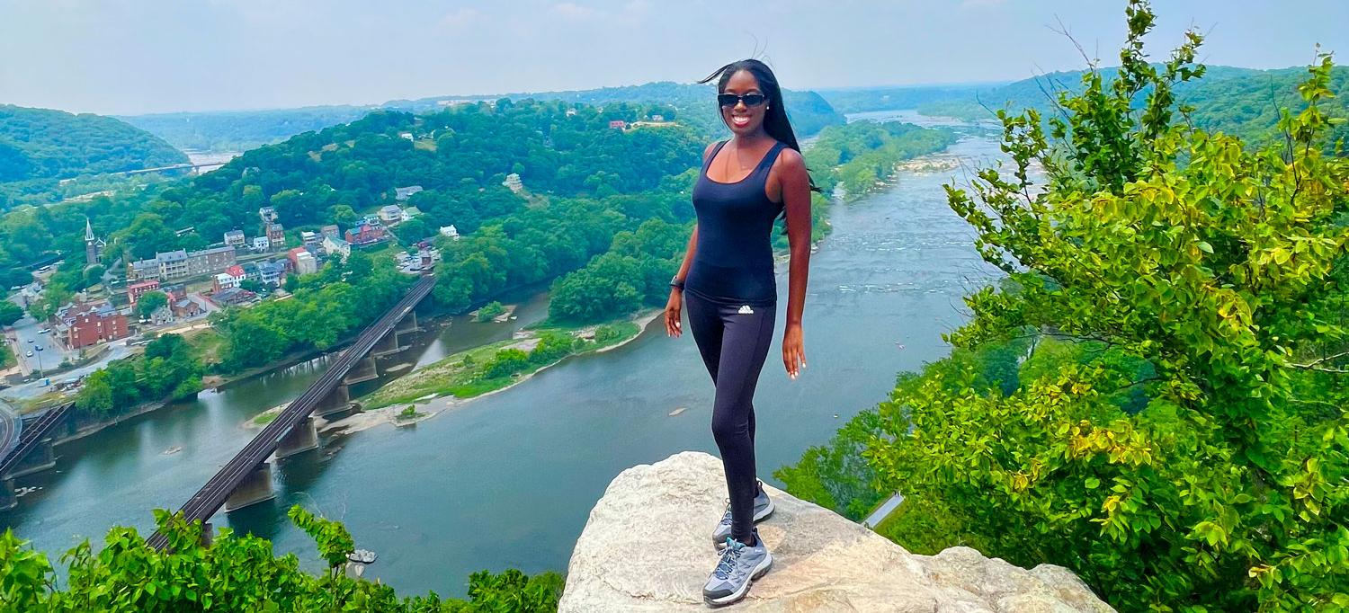 Tiffany Miller Stands on the Top of a Cliff Overlooking a River