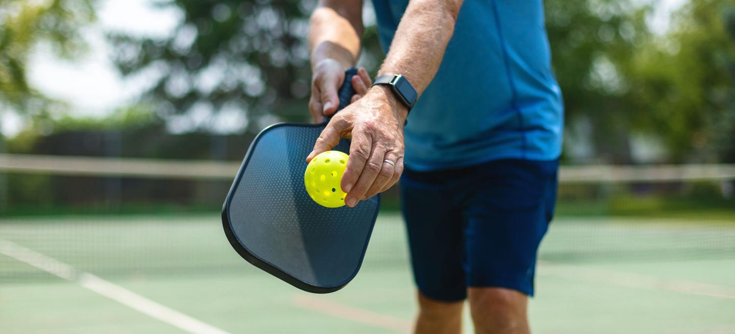 The torso of pickleball player on a court